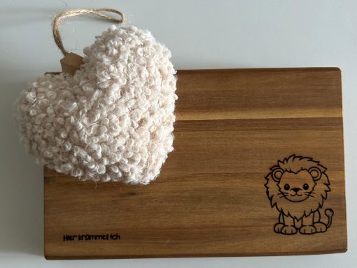 Holzbrett mit einem geprägten Löwen und einem rosa Herz aus flauschigem Material.
