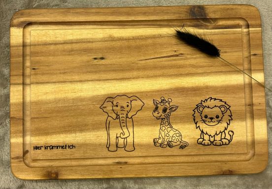 Holzbrett mit gravierten Tiermotiven: Elefant, Giraffe und Löwe.